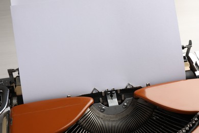Photo of Vintage typewriter with sheet of paper on table, closeup. Space for text