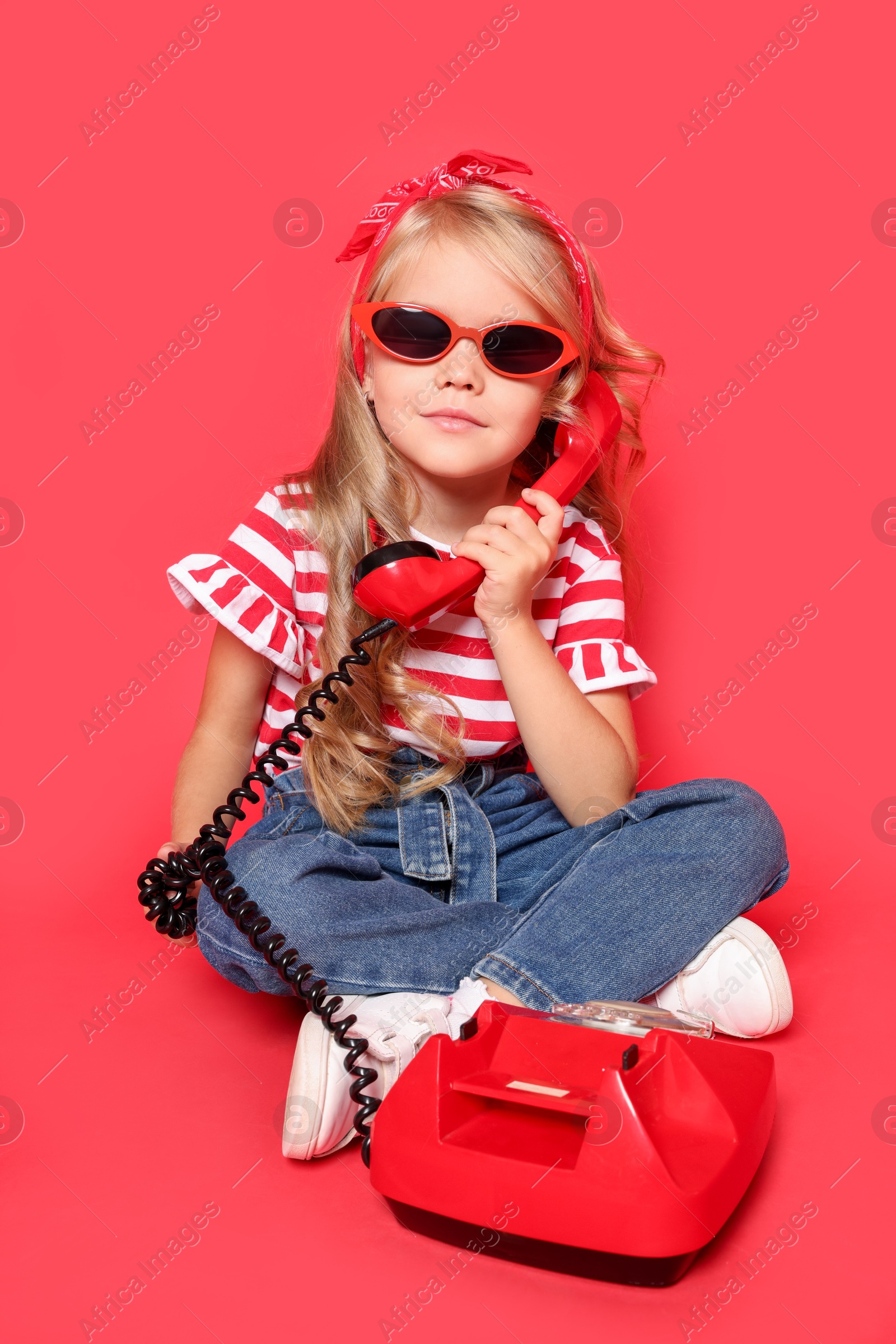 Photo of Cute little girl with telephone on red background