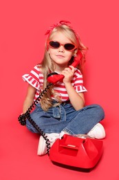 Photo of Cute little girl with telephone on red background