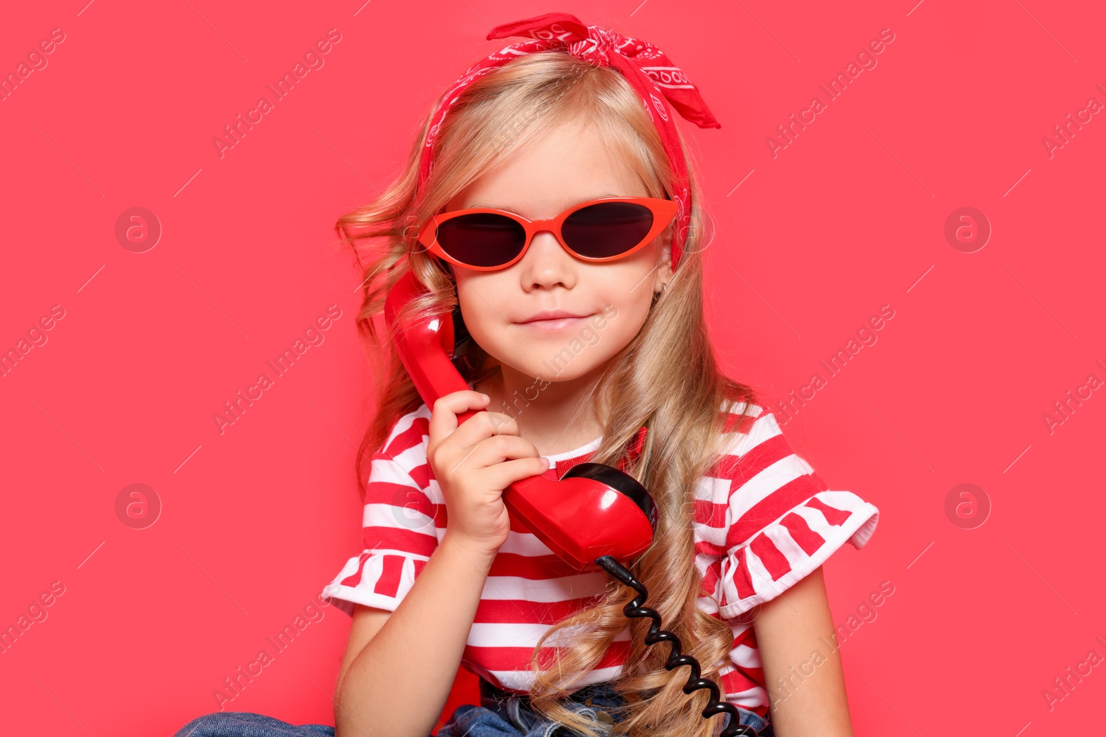 Photo of Cute little girl with handset of telephone on red background