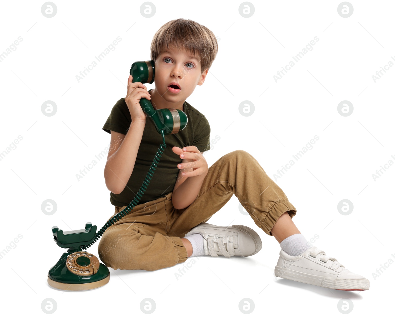 Photo of Cute little boy with vintage telephone on white background