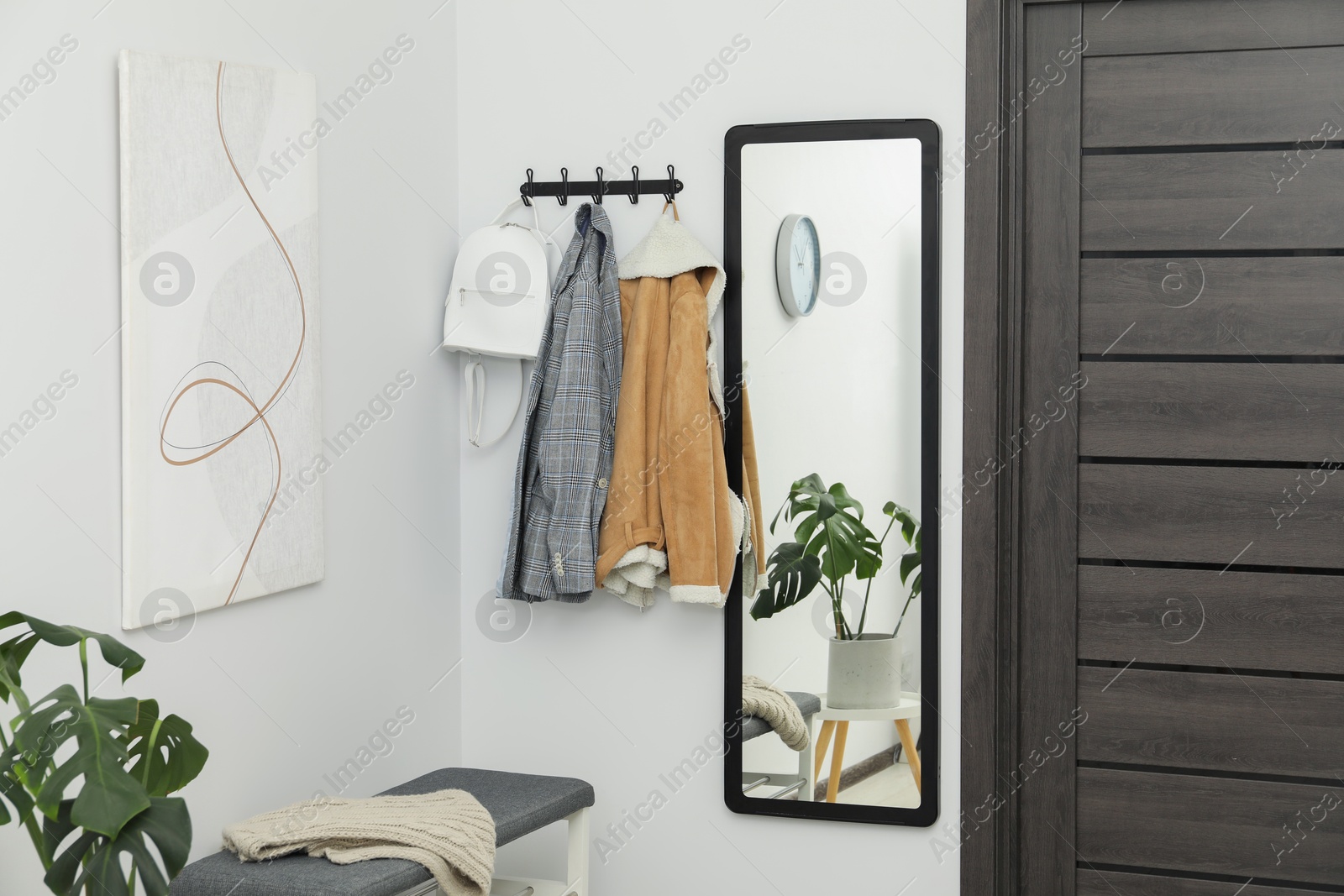 Photo of Mirror, clothes and bench in stylish hallway