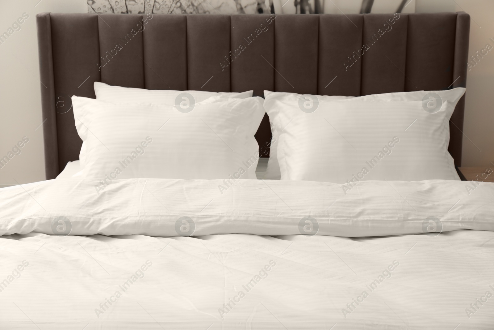 Photo of Comfortable bed with clean linens and pillows indoors