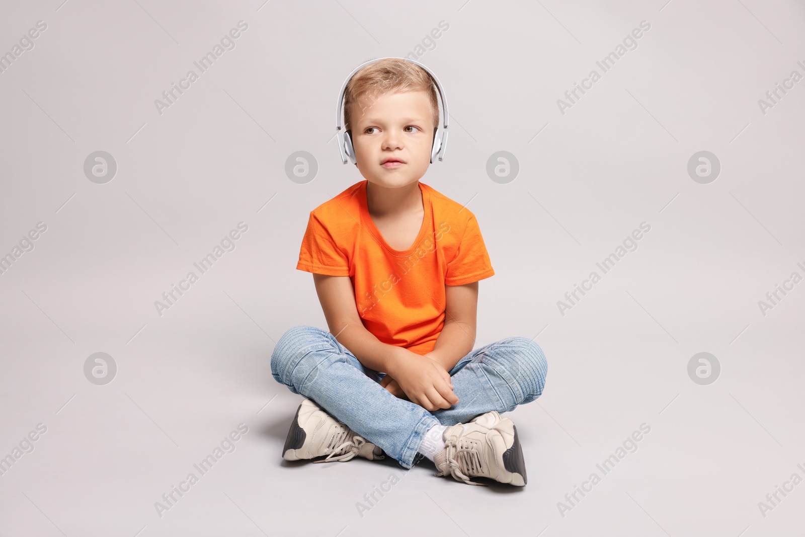 Photo of Little boy listening to music on light grey background