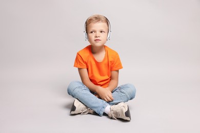 Photo of Little boy listening to music on light grey background