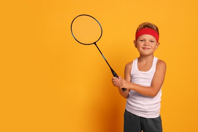 Photo of Little boy with badminton racket on orange background, space for text