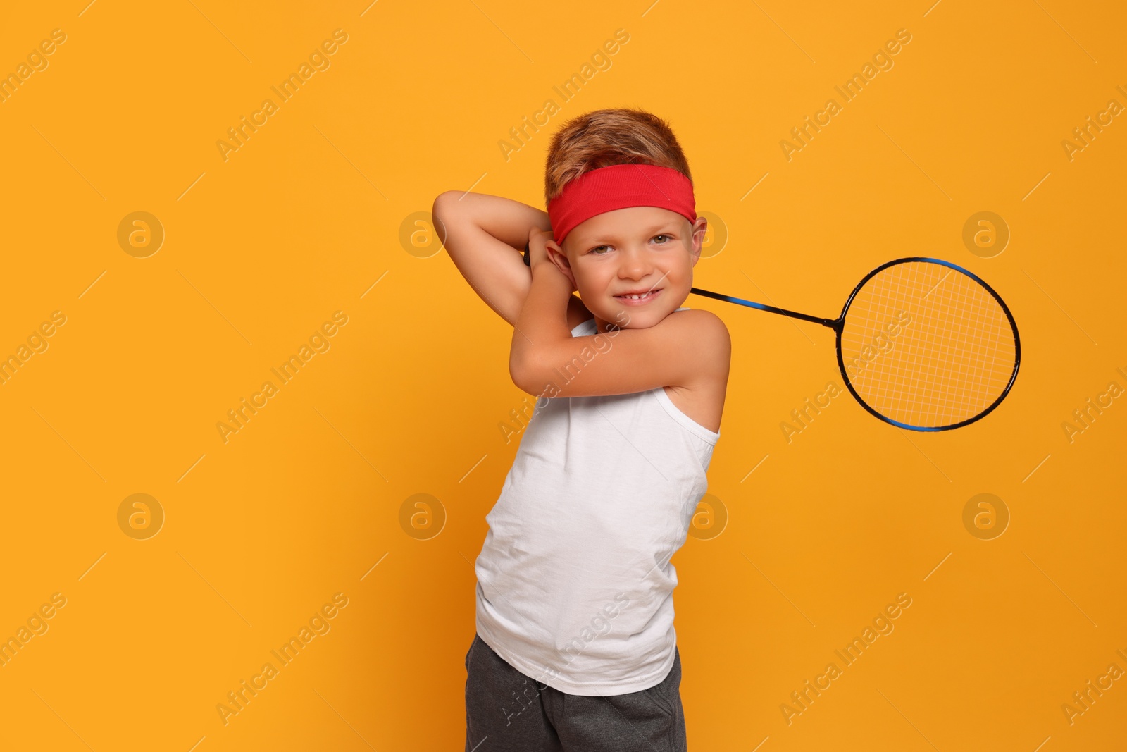 Photo of Little boy with badminton racket on orange background