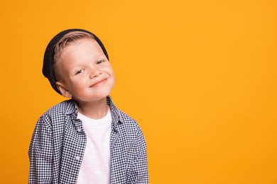 Photo of Portrait of little boy with stylish clothes on orange background, space for text