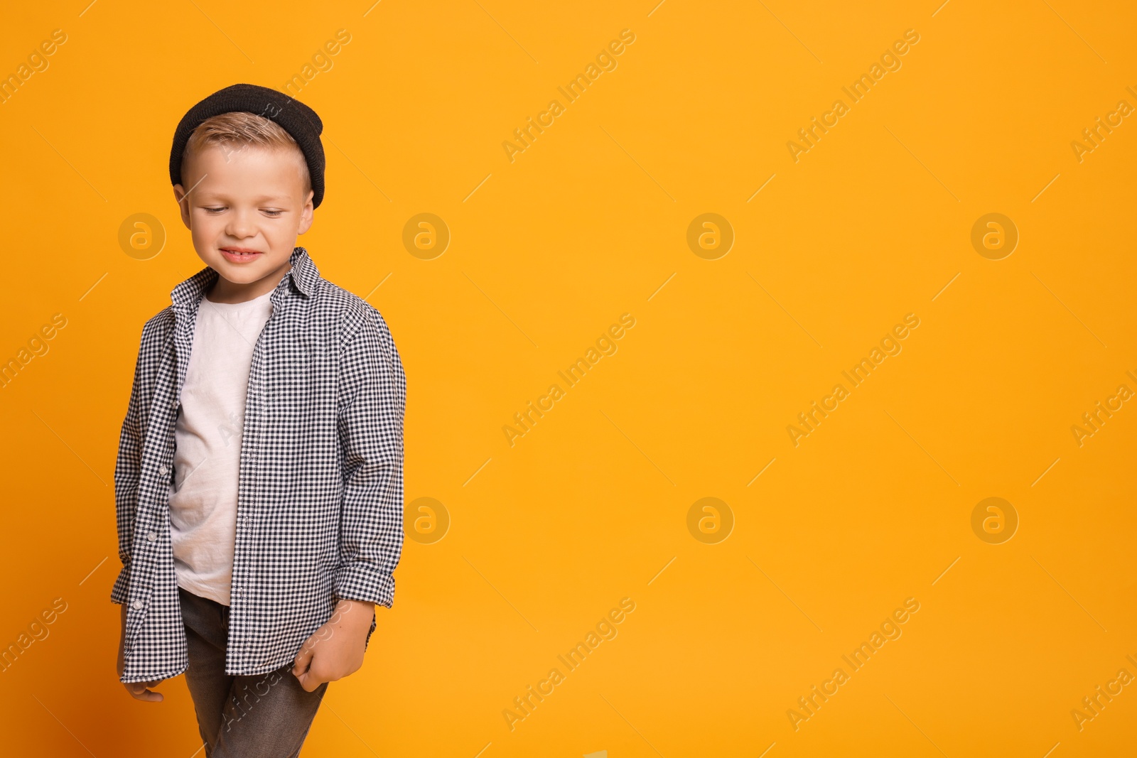 Photo of Portrait of little boy with stylish clothes on orange background, space for text