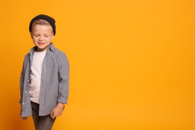 Photo of Portrait of little boy with stylish clothes on orange background, space for text