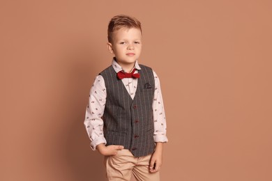 Photo of Portrait of little boy with stylish clothes on brown background