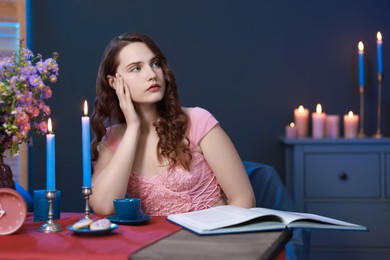 Photo of Beautiful young woman sitting at table in room. Fashion vintage style portrait