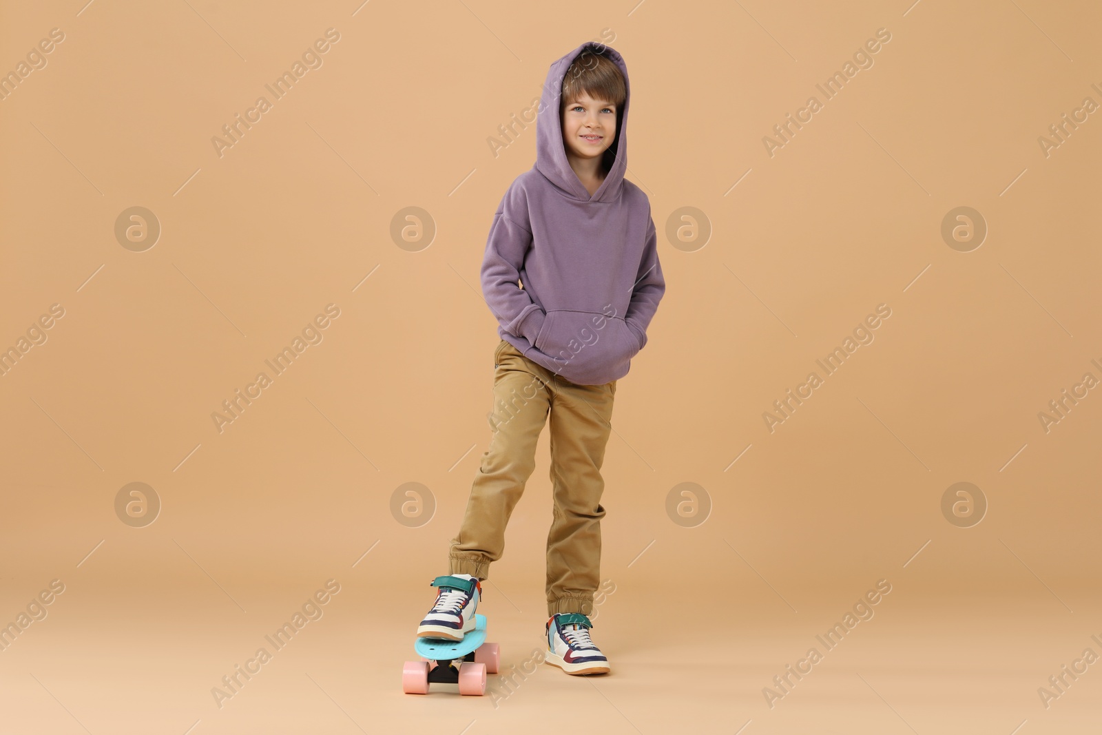 Photo of Little boy with skateboard on beige background