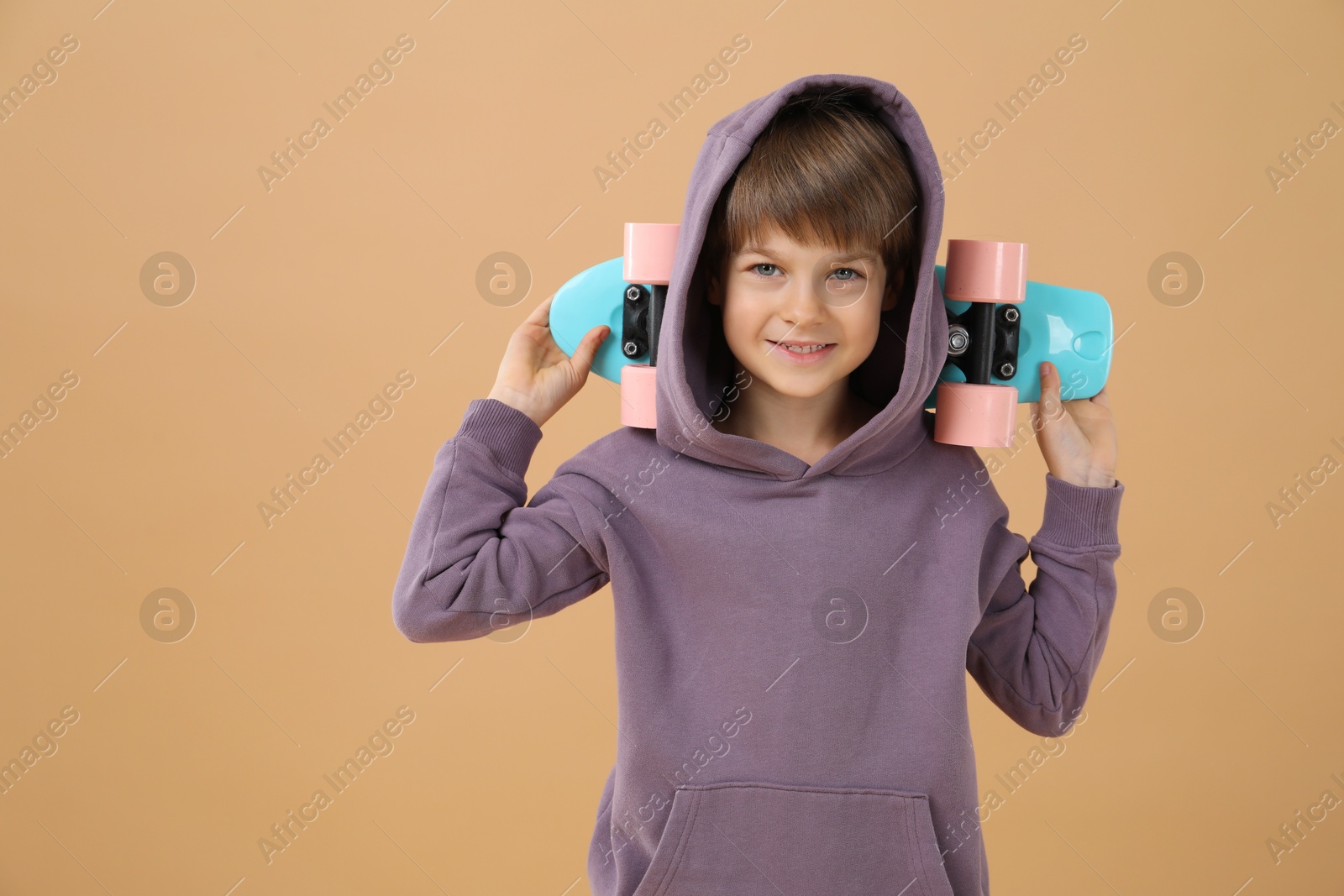 Photo of Little boy with skateboard on beige background