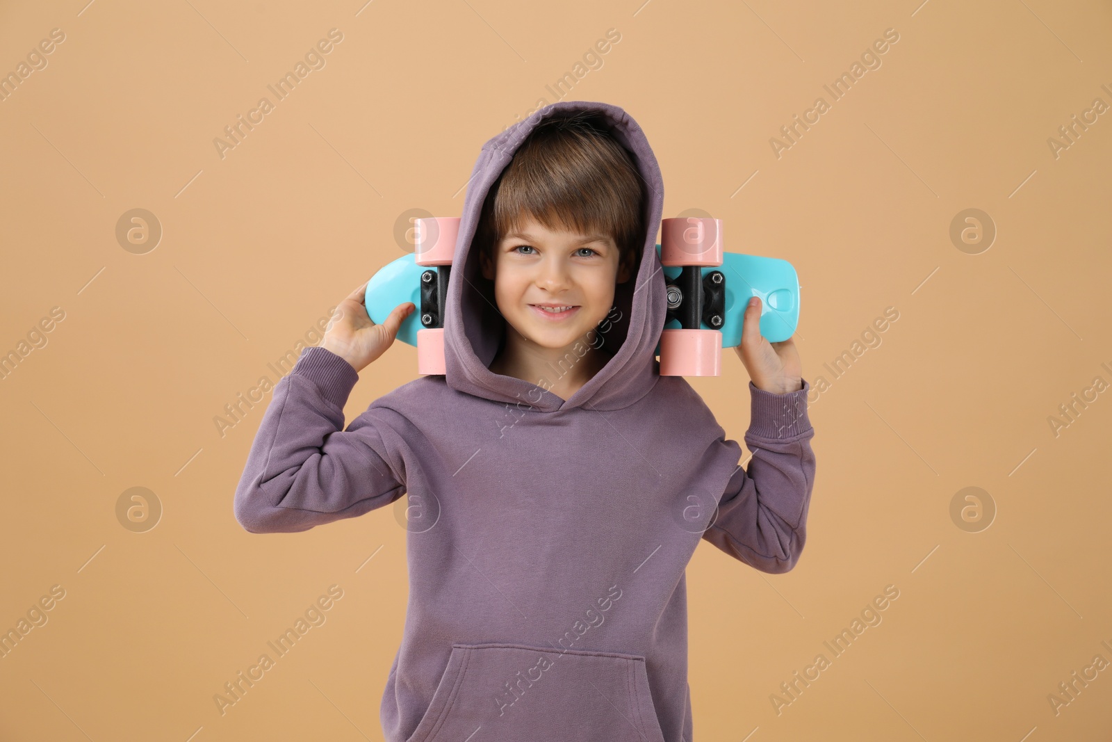 Photo of Little boy with skateboard on beige background