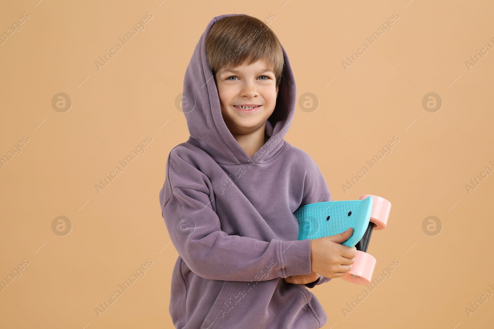 Photo of Little boy with skateboard on beige background