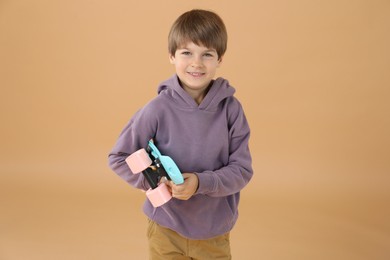 Photo of Little boy with skateboard on beige background