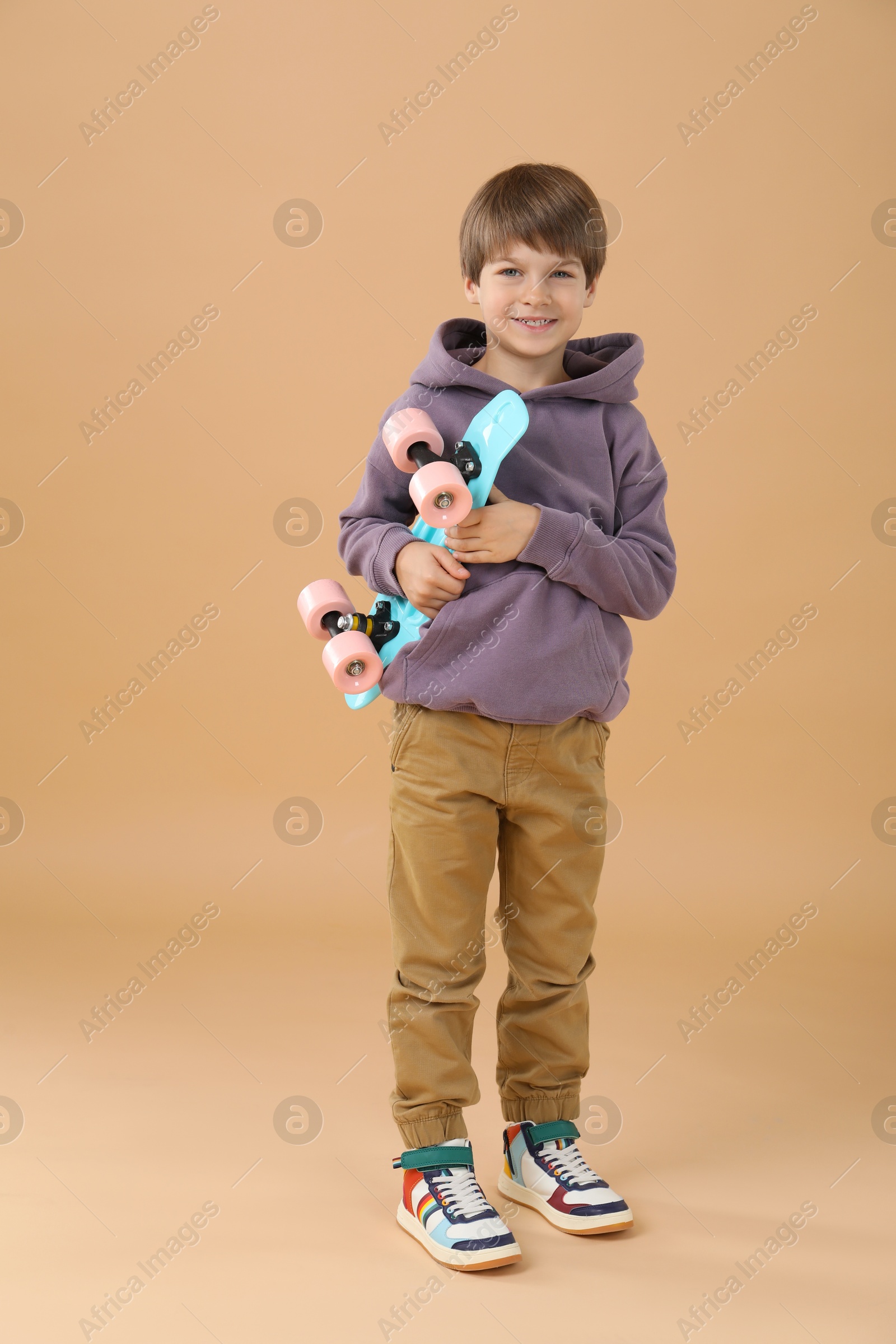 Photo of Little boy with skateboard on beige background