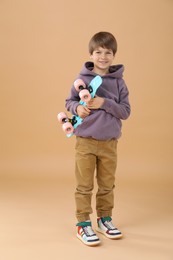 Little boy with skateboard on beige background