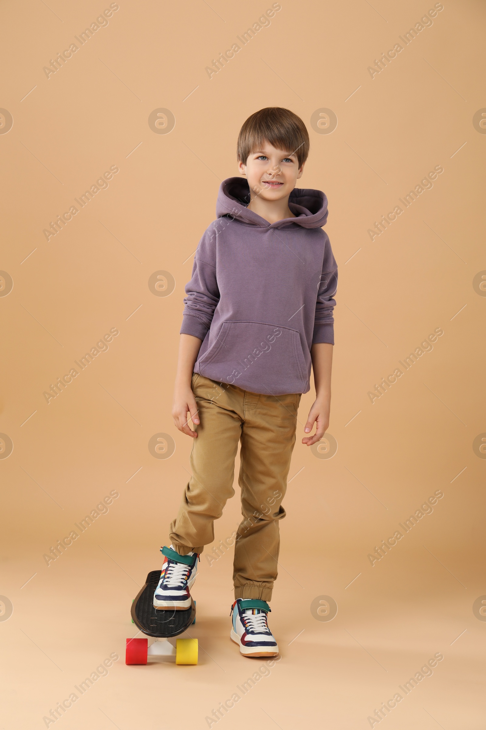 Photo of Little boy with skateboard on beige background