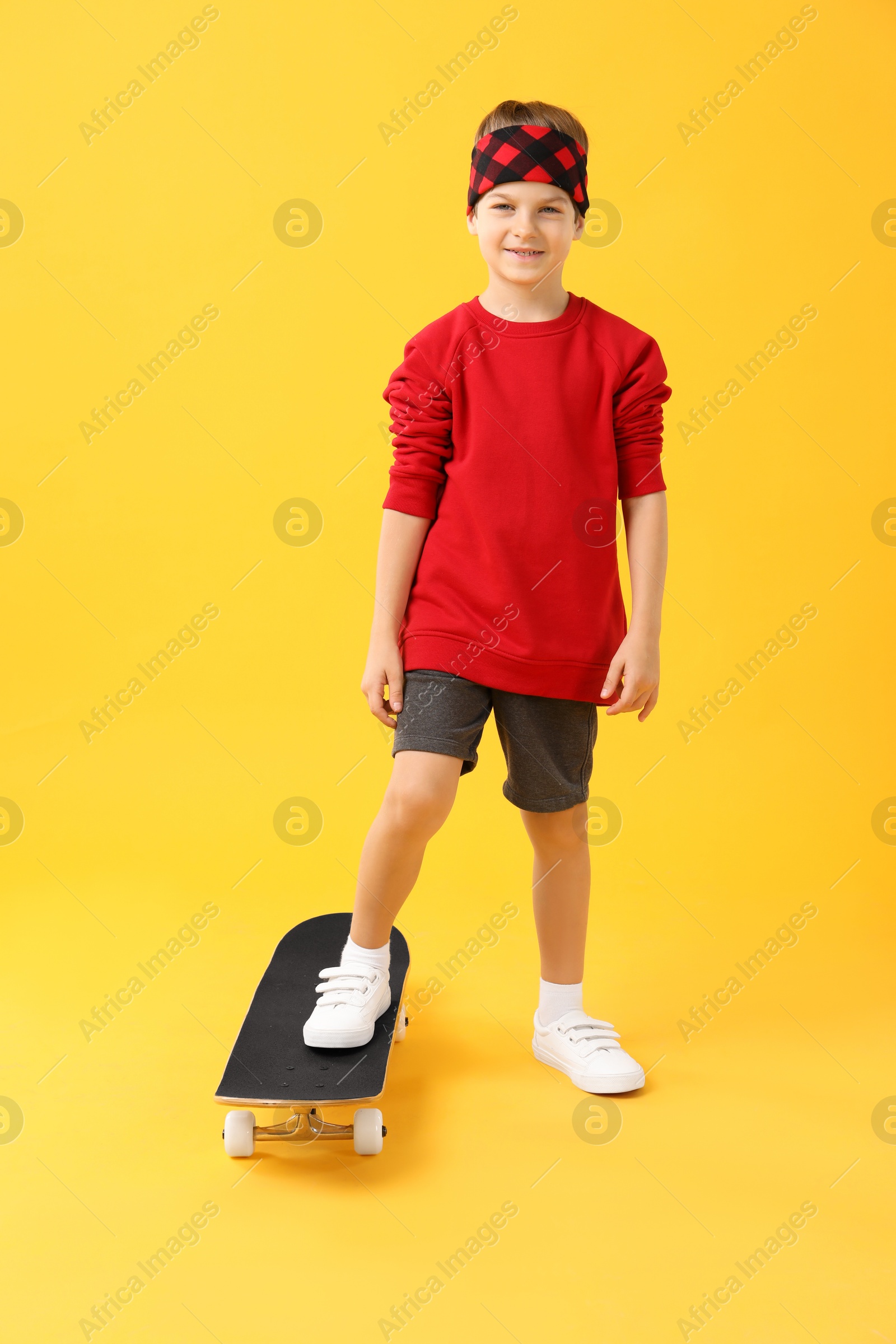 Photo of Little boy with skateboard on yellow background