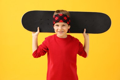 Photo of Little boy with skateboard on yellow background