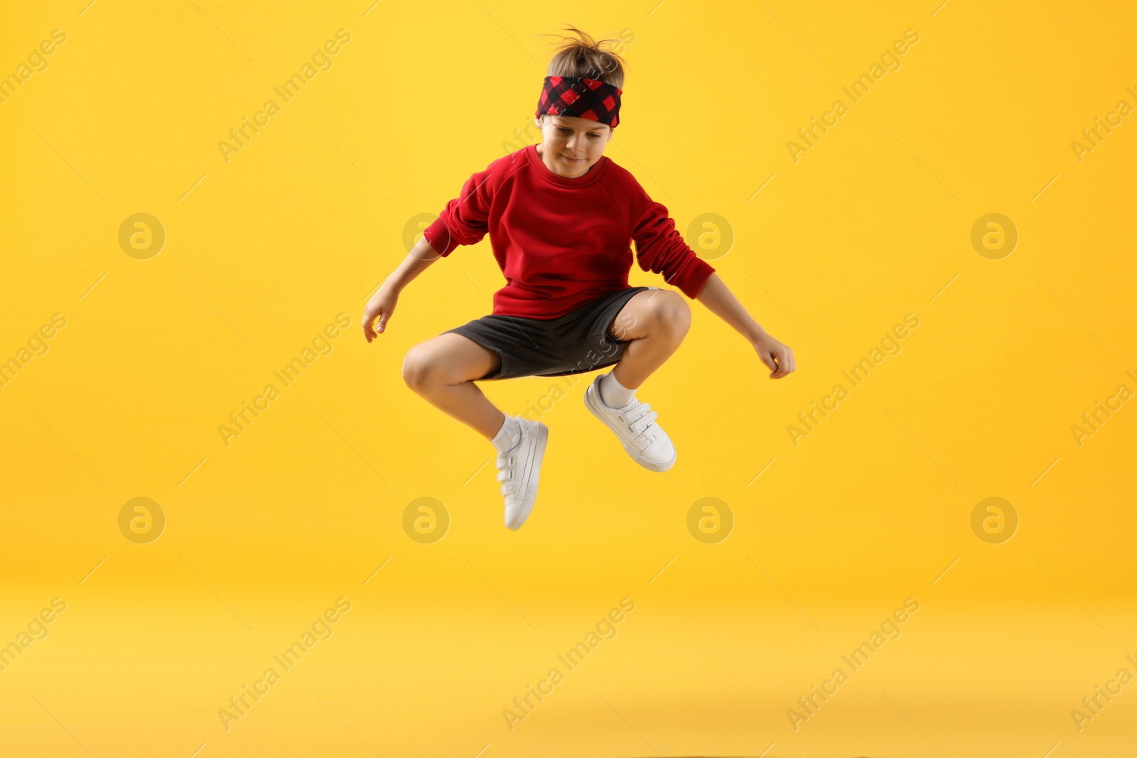 Photo of Happy little boy jumping on yellow background