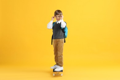 Photo of Little boy with skateboard on yellow background