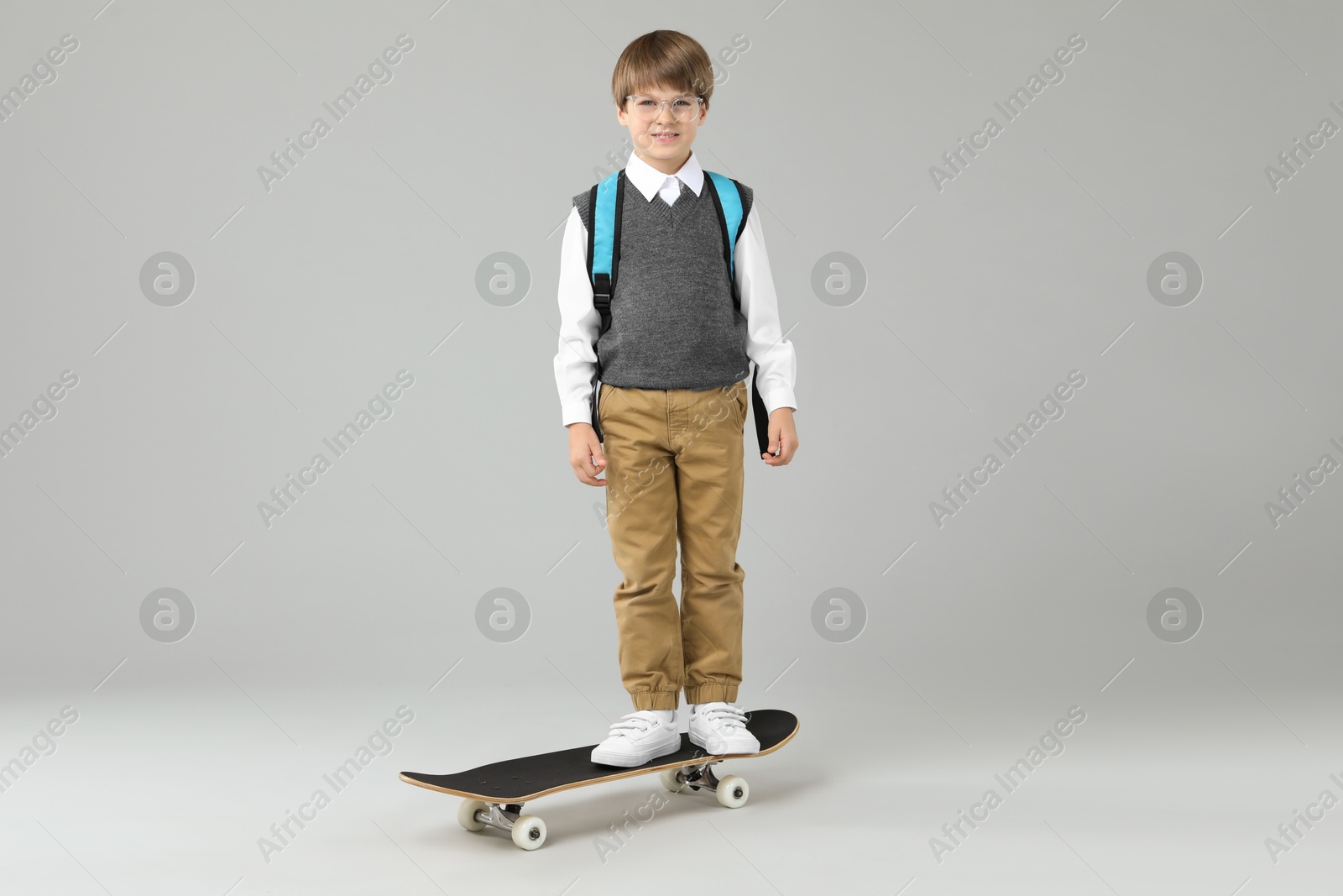 Photo of Little boy with skateboard on light grey background