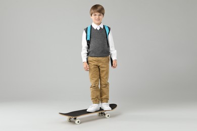 Little boy with skateboard on light grey background