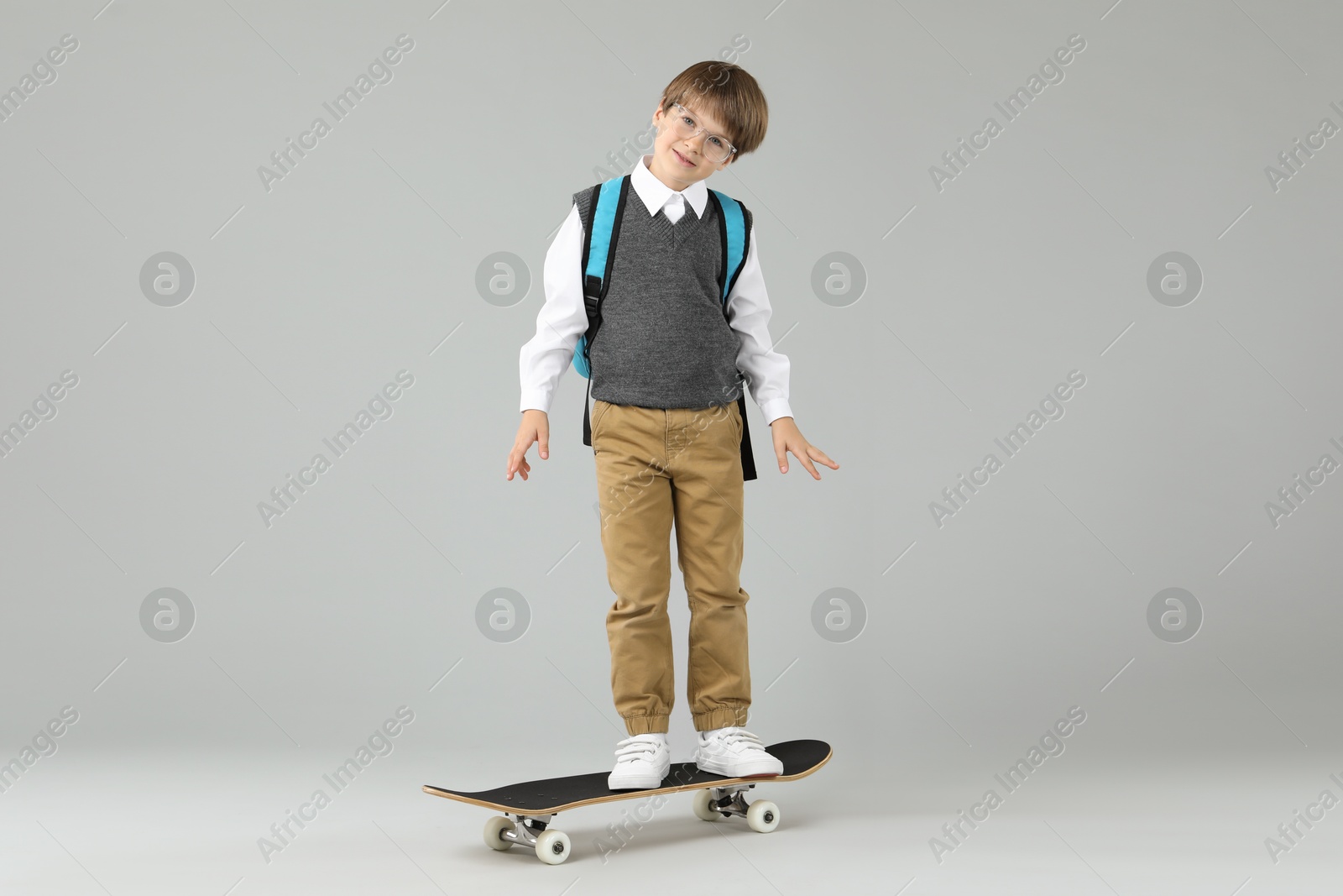 Photo of Little boy with skateboard on light grey background