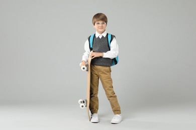 Photo of Little boy with skateboard on light grey background