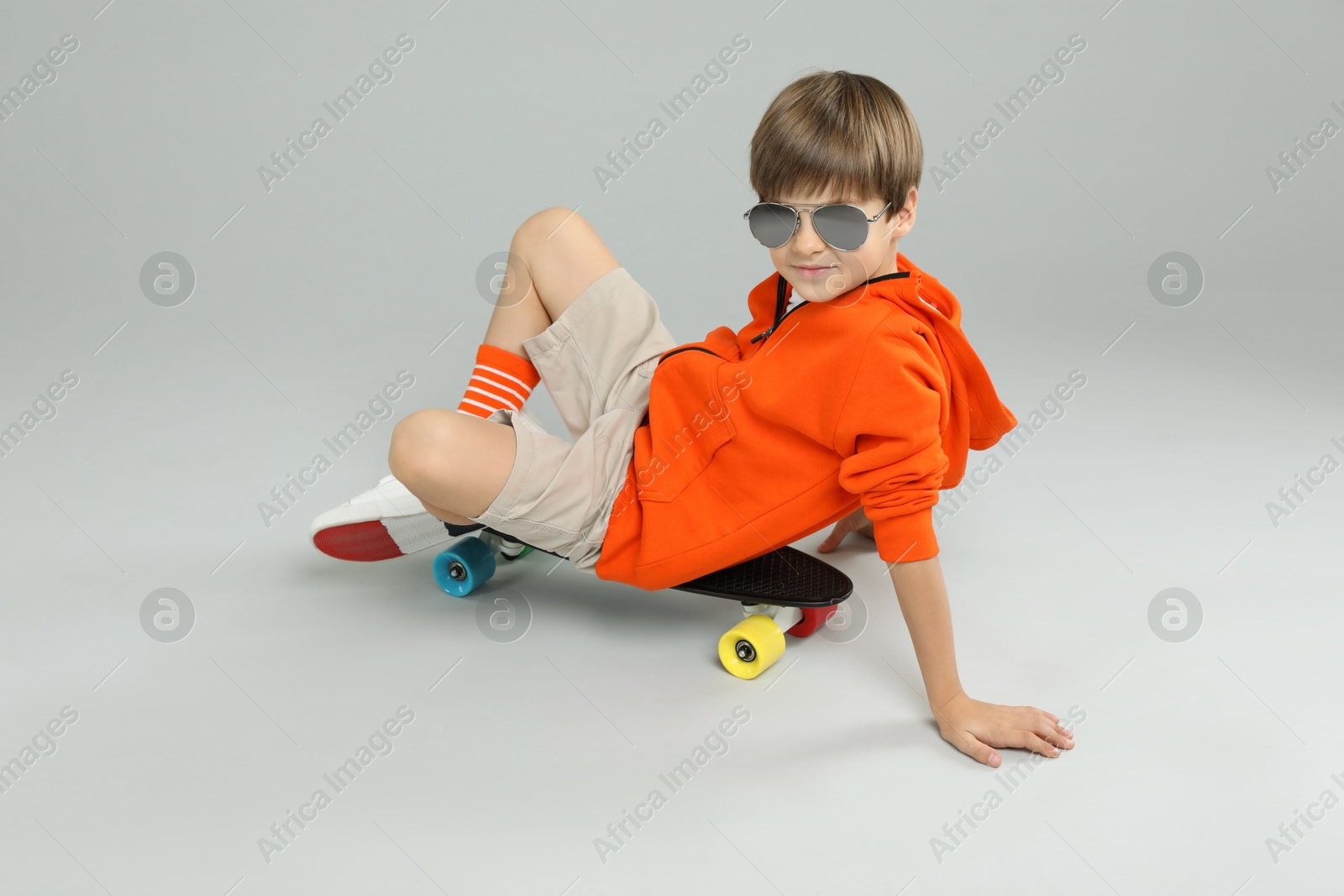 Photo of Little boy with skateboard on light grey background