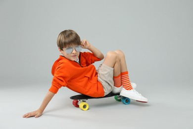 Photo of Little boy with skateboard on light grey background