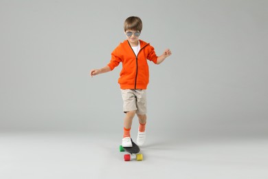 Photo of Little boy with skateboard on light grey background