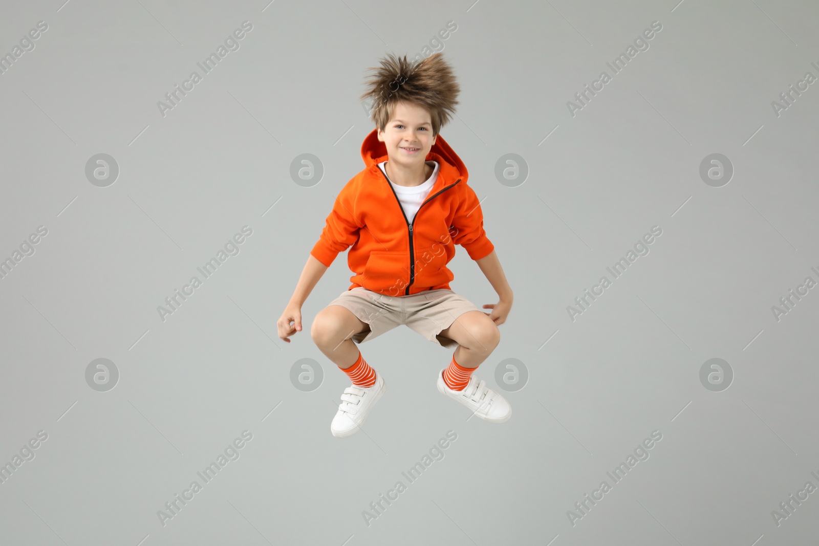 Photo of Happy little boy jumping on light grey background