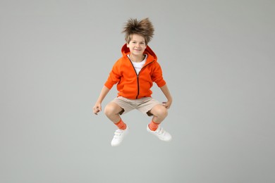 Photo of Happy little boy jumping on light grey background