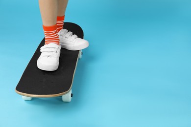 Little boy with skateboard on light blue background, closeup. Space for text