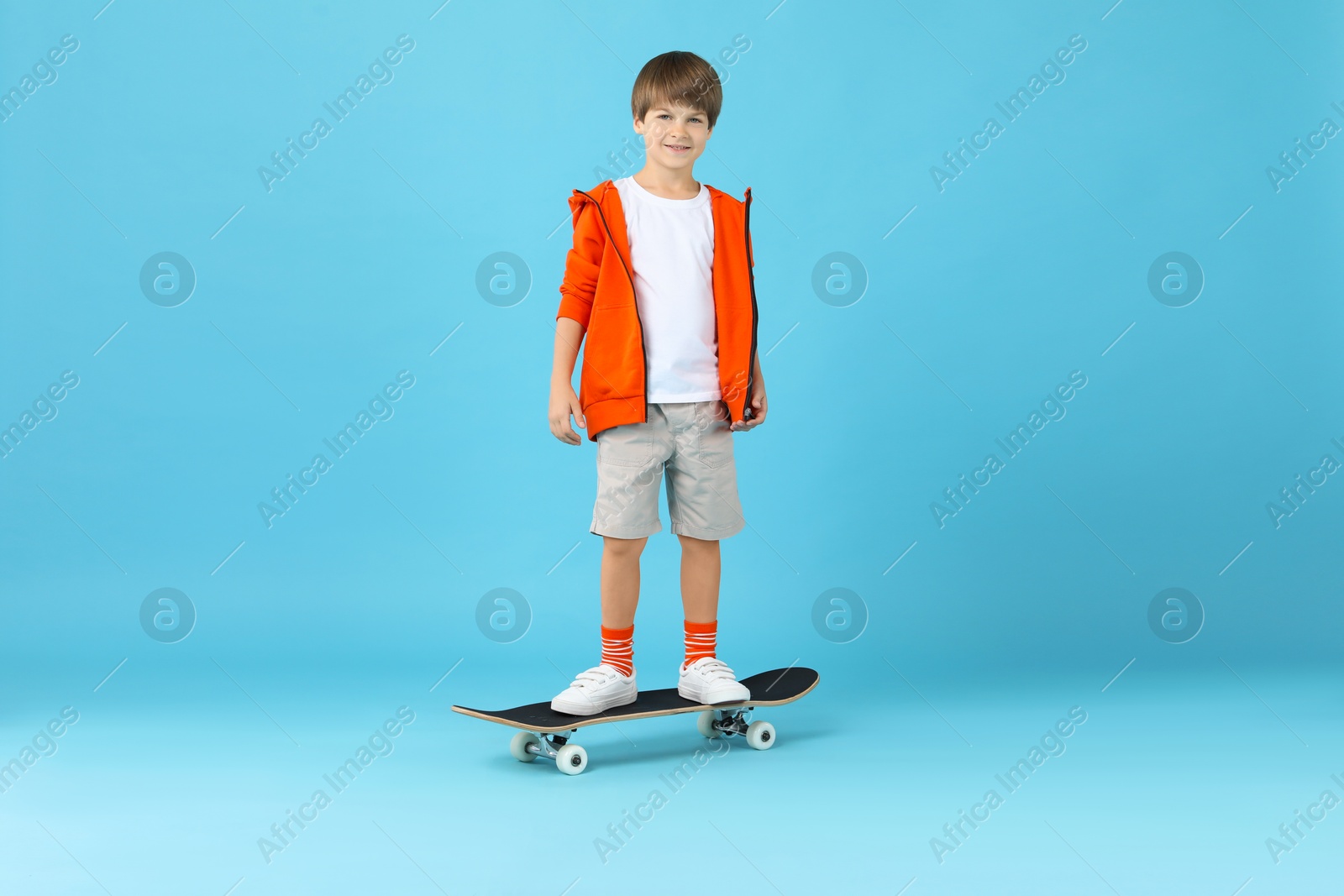 Photo of Little boy with skateboard on light blue background