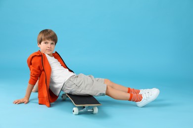 Photo of Little boy with skateboard on light blue background