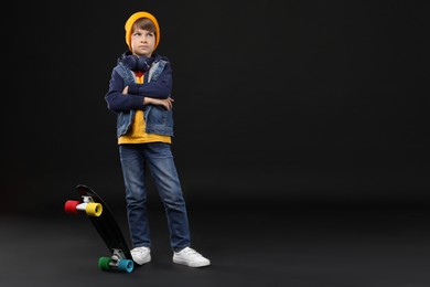 Photo of Little boy with skateboard on black background, space for text