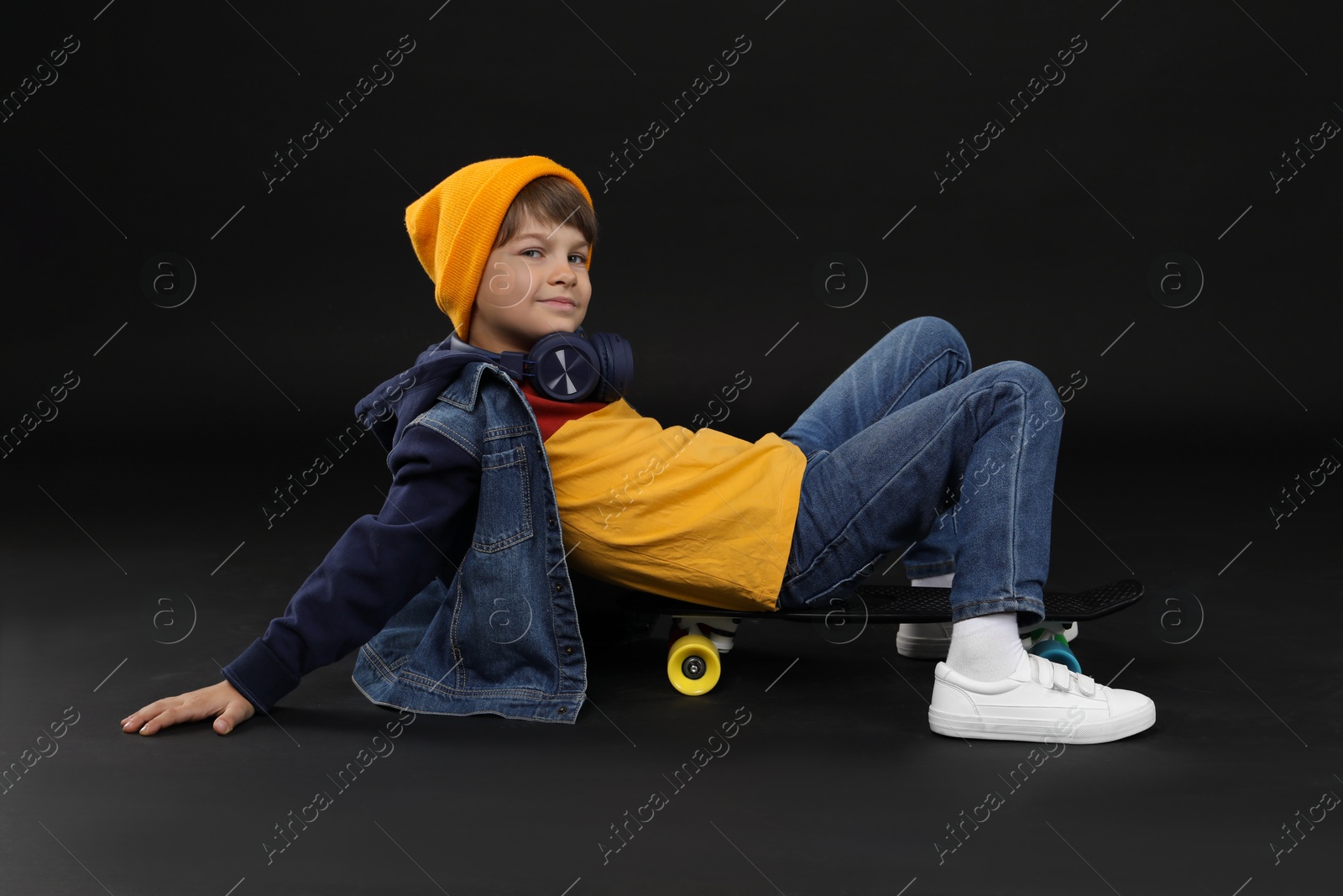 Photo of Little boy with skateboard on black background