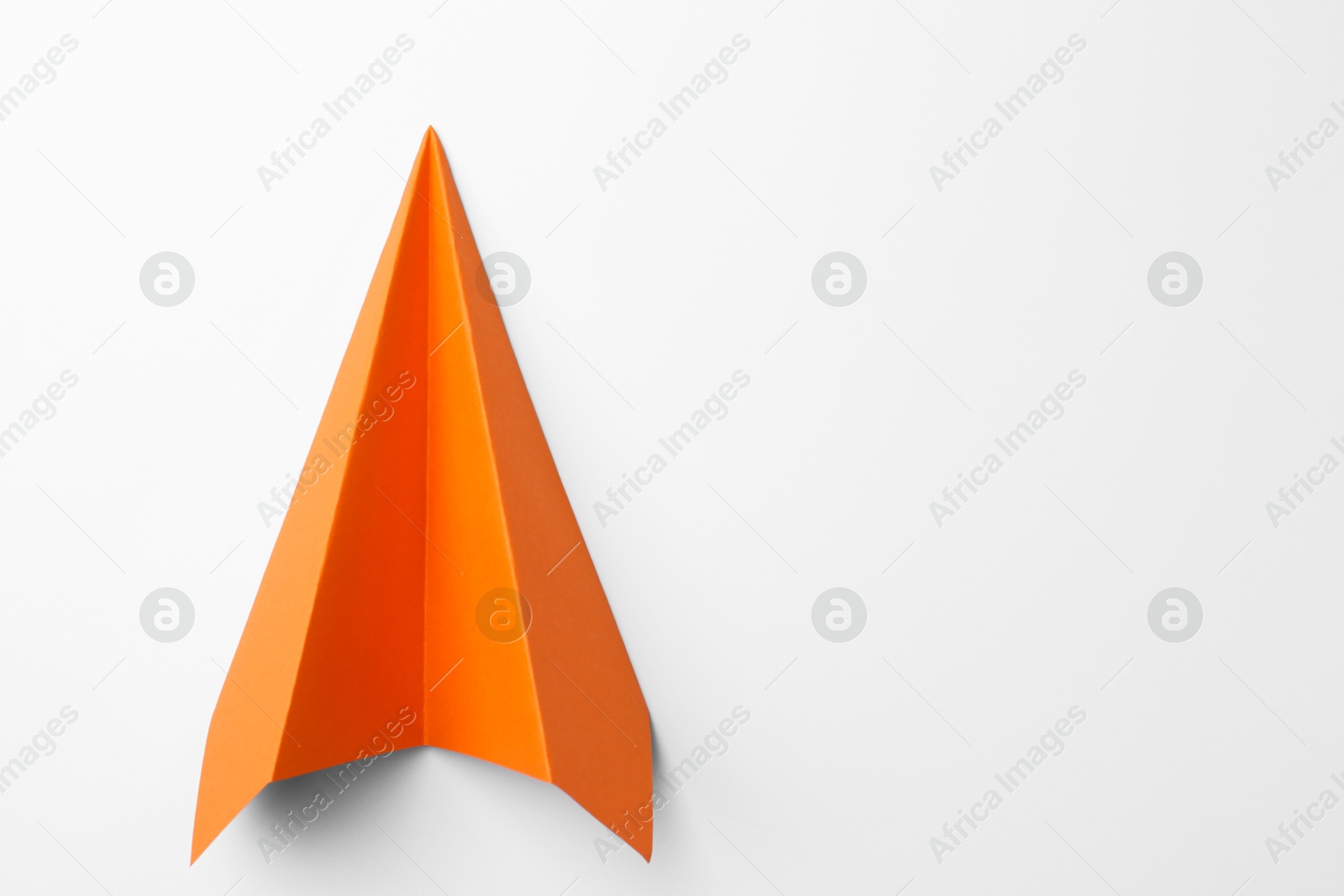 Photo of One handmade orange paper plane on white background, top view. Space for text