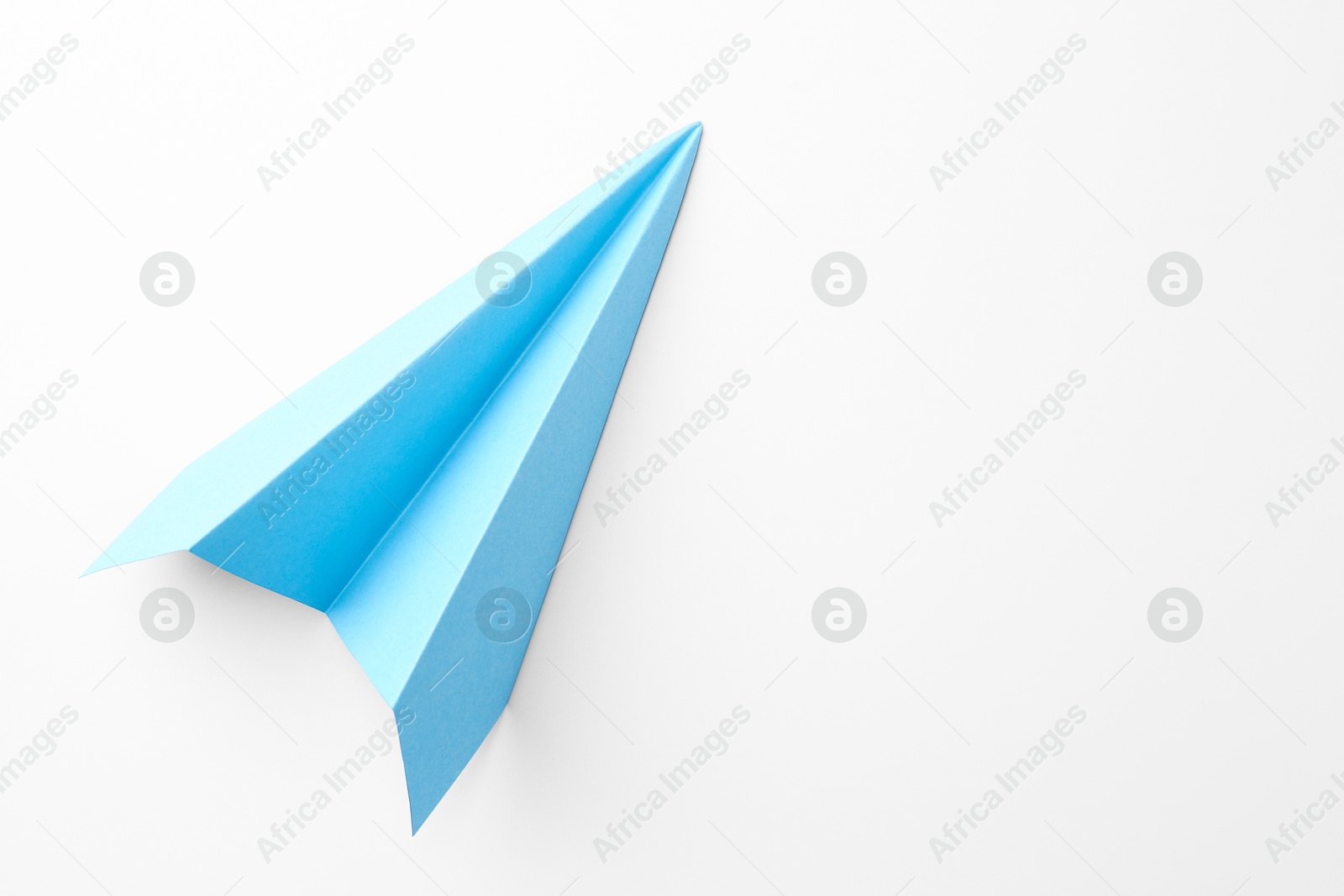 Photo of One handmade light blue paper plane on white background, top view. Space for text