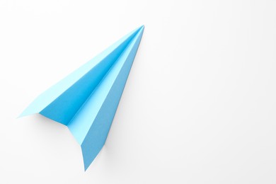 Photo of One handmade light blue paper plane on white background, top view. Space for text