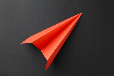 Photo of One handmade orange paper plane on grey background, top view