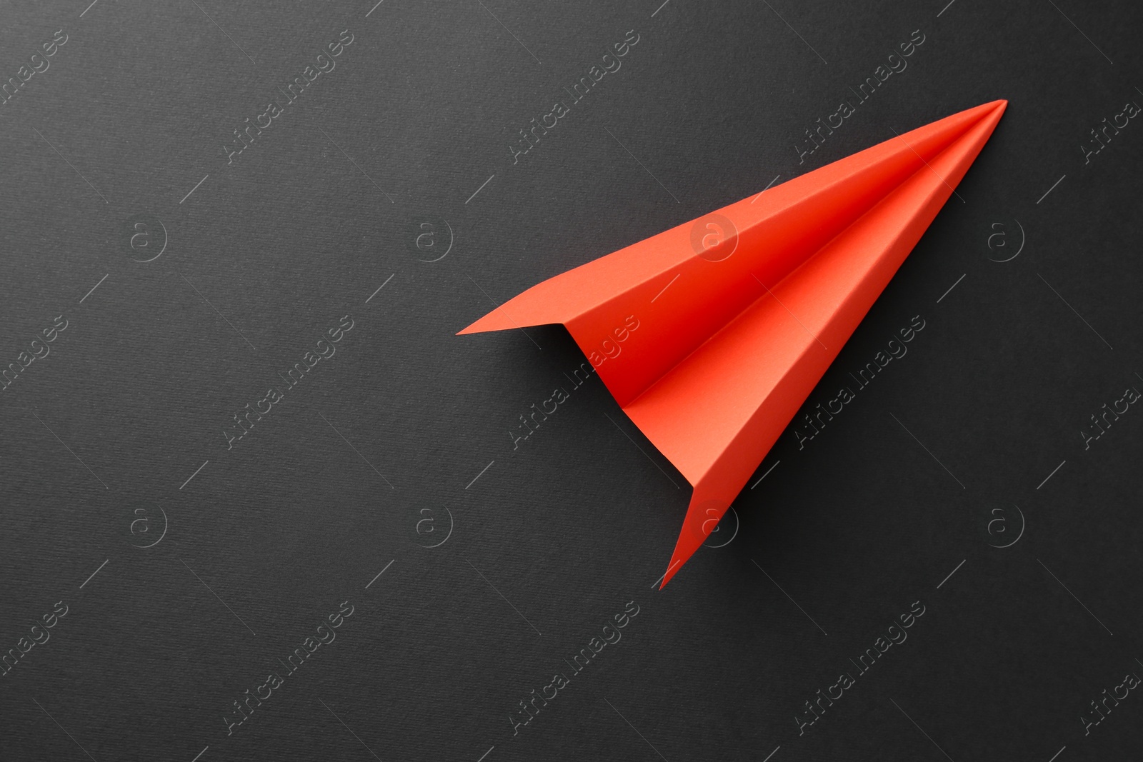 Photo of One handmade orange paper plane on grey background, top view. Space for text