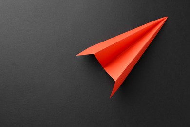 Photo of One handmade orange paper plane on grey background, top view. Space for text