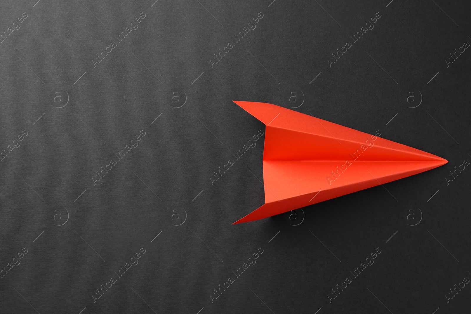 Photo of One handmade orange paper plane on grey background, top view. Space for text