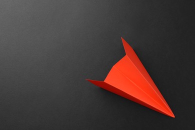 Photo of One handmade orange paper plane on grey background, top view. Space for text